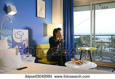 Stock Photography - "Young woman having breakfast in a hotel room, France, Europe". Fotosearch