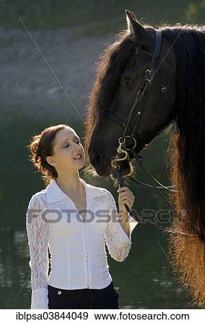 "Young woman holding a black Friesian horse on the lakefront, backlit, Northern Tyrol, Austria, Europe" View Large Photo Image Stock Photo - "Young woman holding a black Friesian horse on the lakefront, backlit, Northern Tyrol, Austria, Europe". Fotosearch