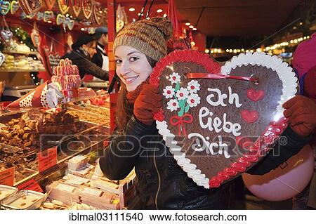 Stock Image - "Young woman holding a Gingerbread heart with inscription """"Ich liebe Dich"""", German for """"I love you"""" at the Christmas market, Esslingen am Neckar, Baden-Wurttemberg, Germany, Europe". Fotosearch