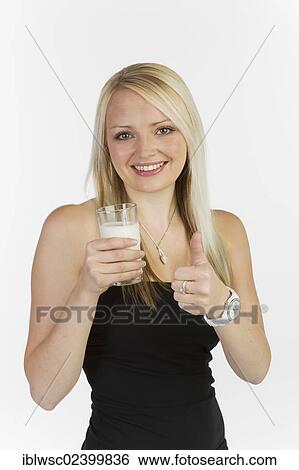 "Young woman holding a glass of milk, making thumbs up gesture" View Large Photo Image Stock Photograph - "Young woman holding a glass of milk, making thumbs up gesture". Fotosearch