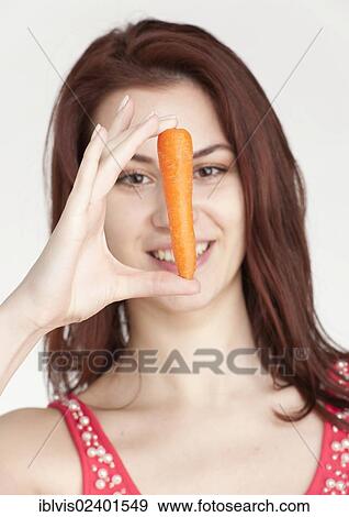 Young woman holding an organic carrot View Large Photo Image Stock Photo - Young woman holding an organic carrot. Fotosearch