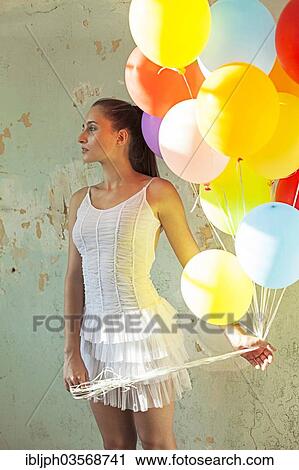 Stock Image - "Young woman holding balloons, Germany, Europe". Fotosearch