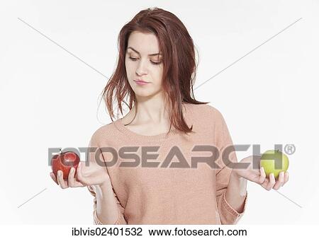 Stock Image - Young woman holding two apples. Fotosearch