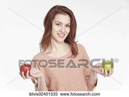 Stock Image - Young woman holding two apples. Fotosearch