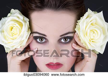 "Young woman holding two yellow roses next to her face, portrait" View Large Photo Image Stock Image - "Young woman holding two yellow roses next to her face, portrait". Fotosearch