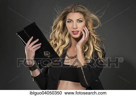 Young woman in a black top and holding a clutch or handbag View Large Photo Image Stock Image - Young woman in a black top and holding a clutch or handbag. Fotosearch