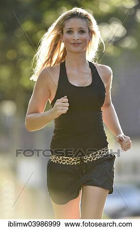 Stock Photo - "Young woman jogging in summer, Germany, Europe". Fotosearch