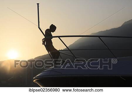 "Young woman leaning against the railing of the bow of a motor yacht in the evening with backlighting, Principality of Monaco, Cote d'Azur, Mediterranean, Europe" View Large Photo Image Stock Image - "Young woman leaning against the railing of the bow of a motor yacht in the evening with backlighting, Principality of Monaco, Cote d'Azur, Mediterranean, Europe". Fotosearch