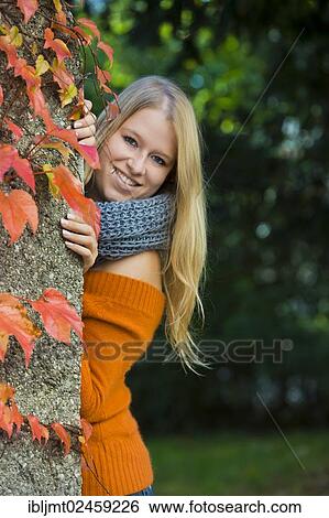 Young woman looking from behind a wall with colorful autumn leaves View Large Photo Image Stock Photograph - Young woman looking from behind a wall with colorful autumn leaves. Fotosearch