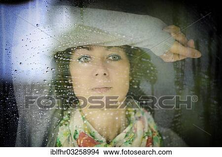 Picture - "Young woman looking through a window on a rainy day, Grevenbroich, Rhineland, North Rhine-Westphalia, Germany, Europe". Fotosearch