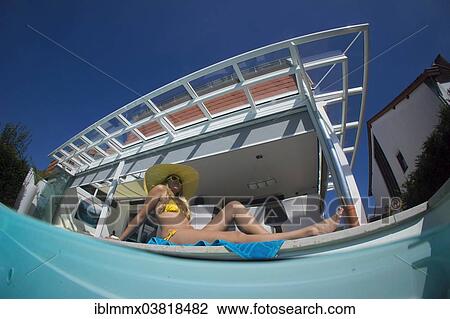 Stock Image - "Young woman lying beside a private pool, Germany, Europe". Fotosearch