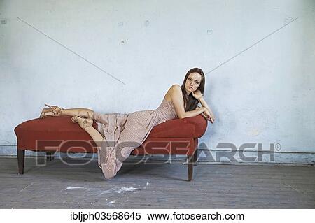 Stock Photography - "Young woman lying on a chaise longue in a room in need of redecoration, Germany, Europe". Fotosearch