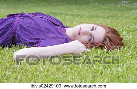 Young woman lying on the grass in a park View Large Photo Image Stock Photo - Young woman lying on the grass in a park. Fotosearch