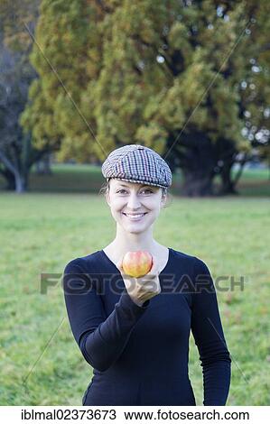 Stock Image - Young woman offering an apple. Fotosearch