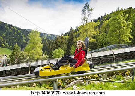 Stock Image - "Young woman on a summer toboggan run, Steinwasenpark in Oberried, Black Forest, Baden-Wurttemberg, Germany, Europe". Fotosearch