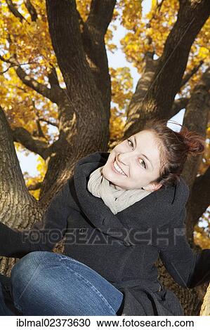 Young woman on a tree in autumn View Large Photo Image Stock Image - Young woman on a tree in autumn. Fotosearch