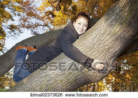 Young woman on a tree in autumn View Large Photo Image Stock Photograph - Young woman on a tree in autumn. Fotosearch