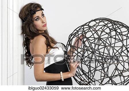 Stock Photo - Young woman posing beside a wire ball. Fotosearch