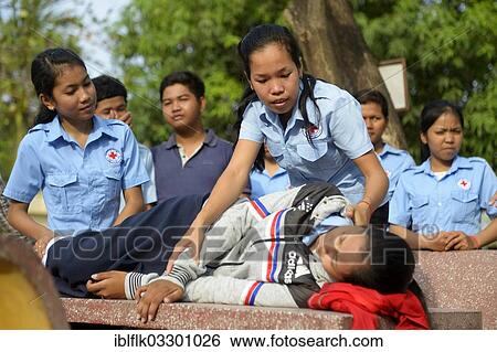 Stock Photograph - "Young woman positioning a patient in the recovery position, training of young people from the community to become first aid workers by the Red Cross, Tropeng Village, Bathi District, Takeo Province, Cambodia, Asia". Fotosearch