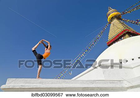 Stock Photo - "Young woman practicing yoga at Boudnanath stupa, showing the Natarajasana pose, or Lord Shiva's pose, Kathmandu Valley, Kathmandu, Kathmandu District, Bagmati Zone, Nepal, Asia". Fotosearch