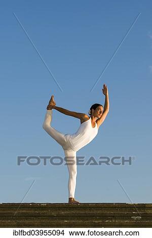 Picture - "Young woman practising Hatha yoga, outdoors, showing the pose Saral Natarajasana, preparatory Lord Shiva's pose". Fotosearch