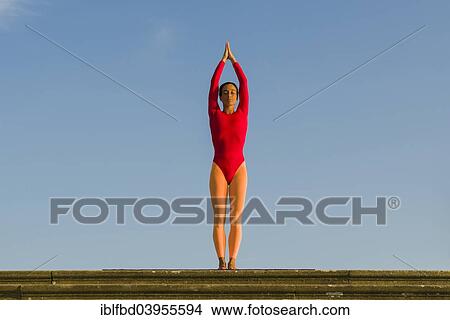 Picture - "Young woman practising Hatha yoga, outdoors, showing the pose Tadasana, Pranamasana, Prayer pose". Fotosearch