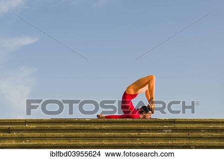 Picture - "Young woman practising Hatha yoga, outdoors, showing the pose poorna Shalabhasana, full Locust". Fotosearch