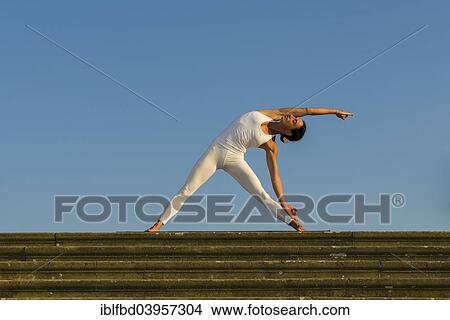 "Young woman practising Hatha yoga, outdoors, showing the pose Trikonasana, Triangle" View Large Photo Image Picture - "Young woman practising Hatha yoga, outdoors, showing the pose Trikonasana, Triangle". Fotosearch