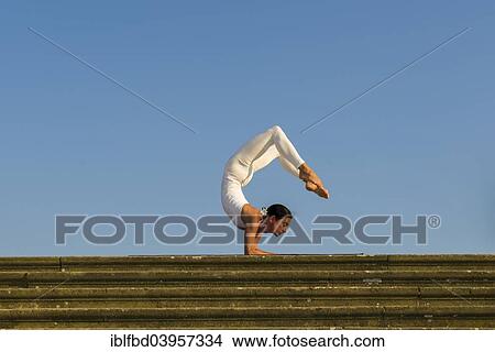"Young woman practising Hatha yoga, outdoors, showing the pose Vrischikasana, Scorpion pose" View Large Photo Image Picture - "Young woman practising Hatha yoga, outdoors, showing the pose Vrischikasana, Scorpion pose". Fotosearch
