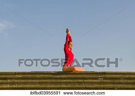 Stock Image - "Young woman practising Hatha yoga, outdoors, showing the pose Padmasana, Lotus pose". Fotosearch