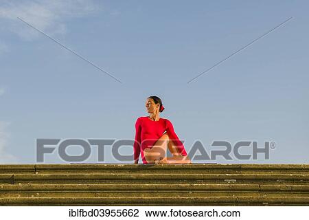 Stock Image - "Young woman practising Hatha yoga, outdoors, showing the pose Ardha Matsyendrasana, half spinal twist". Fotosearch
