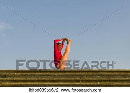 Stock Image - "Young woman practising Hatha yoga, outdoors, showing the pose Urdhva Mukha Pashchimottanasana, unsupported back stretching pose". Fotosearch