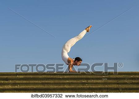 "Young woman practising Hatha yoga, outdoors, showing the pose Vrischikasana, Scorpion pose" View Large Photo Image Stock Image - "Young woman practising Hatha yoga, outdoors, showing the pose Vrischikasana, Scorpion pose". Fotosearch