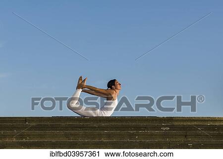 "Young woman practising Hatha yoga, outdoors, showing the pose Dhanurasana, Bow pose" View Large Photo Image Stock Image - "Young woman practising Hatha yoga, outdoors, showing the pose Dhanurasana, Bow pose". Fotosearch
