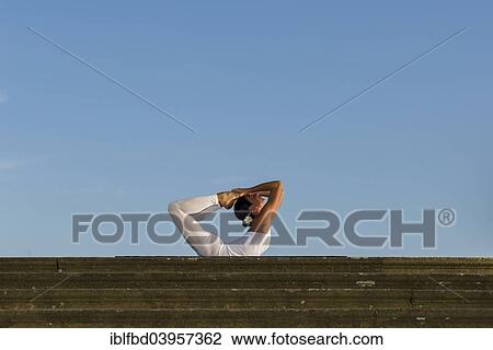 "Young woman practising Hatha yoga, outdoors, showing the pose Dhanurasana, Bow pose" View Large Photo Image Stock Image - "Young woman practising Hatha yoga, outdoors, showing the pose Dhanurasana, Bow pose". Fotosearch