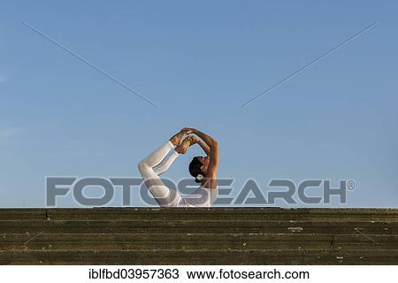 "Young woman practising Hatha yoga, outdoors, showing the pose Dhanurasana, Bow pose" View Large Photo Image Stock Image - "Young woman practising Hatha yoga, outdoors, showing the pose Dhanurasana, Bow pose". Fotosearch