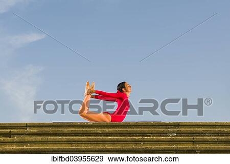 "Young woman practising Hatha yoga, outdoors, showing the pose Dhanurasana, Bow pose" View Large Photo Image Stock Photo - "Young woman practising Hatha yoga, outdoors, showing the pose Dhanurasana, Bow pose". Fotosearch