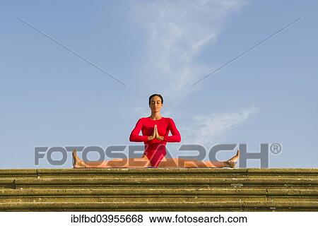 Stock Photo - "Young woman practising Hatha yoga, outdoors, showing the pose Samakonasana, right angle pose, side split". Fotosearch