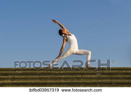 "Young woman practising Hatha yoga, outdoors, showing the pose Virabhadrasana, Warrior pose" View Large Photo Image Stock Photo - "Young woman practising Hatha yoga, outdoors, showing the pose Virabhadrasana, Warrior pose". Fotosearch