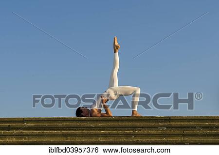 "Young woman practising Hatha yoga, outdoors, showing the pose variation of Halasana, Supta konasana, variation of Plough" View Large Photo Image Stock Photograph - "Young woman practising Hatha yoga, outdoors, showing the pose variation of Halasana, Supta konasana, variation of Plough". Fotosearch