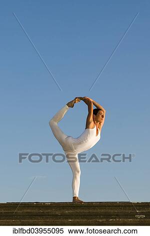 Stock Photography - "Young woman practising Hatha yoga, outdoors, showing the pose Natarajasana, Lord Shiva's pose". Fotosearch