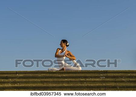 Stock Photography - "Young woman practising Hatha yoga, outdoors, showing the pose Kapotasana, Pigeon pose". Fotosearch