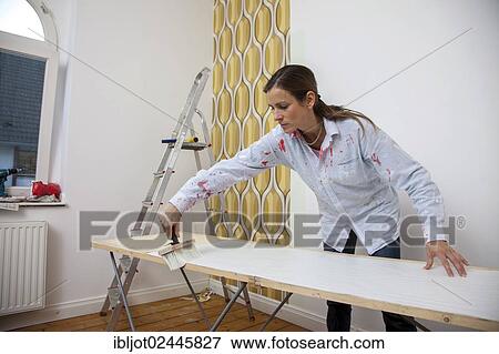 Young woman preparing wallpaper for wallpapering a wall View Large Photo Image Stock Photo - Young woman preparing wallpaper for wallpapering a wall. Fotosearch