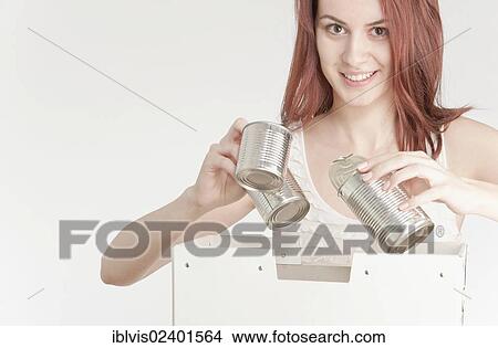Picture - Young woman recycling tin cans. Fotosearch