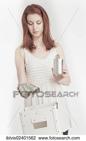 Stock Image - Young woman recycling tin cans. Fotosearch