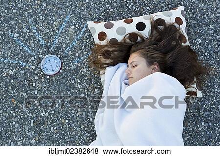 "Young woman resting her head on a pillow, lying on the ground covered with a blanket, painted alarm clock ringing, taken from above" View Large Photo Image Stock Photo - "Young woman resting her head on a pillow, lying on the ground covered with a blanket, painted alarm clock ringing, taken from above". Fotosearch