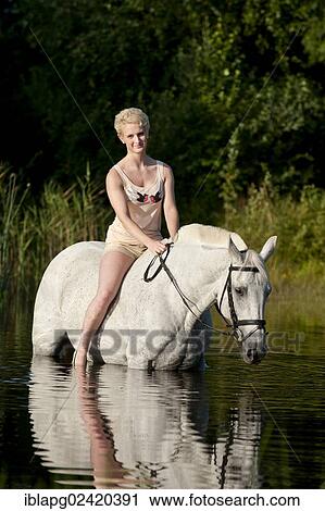 Young woman riding bareback on a Hanoverian horse through a lake View Large Photo Image Stock Image - Young woman riding bareback on a Hanoverian horse through a lake. Fotosearch