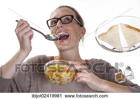 Young woman sitting at a glass table eating clear vegetable soup View Large Photo Image Stock Image - Young woman sitting at a glass table eating clear vegetable soup. Fotosearch