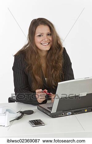 Young woman sitting at a laptop View Large Photo Image Stock Photo - Young woman sitting at a laptop. Fotosearch