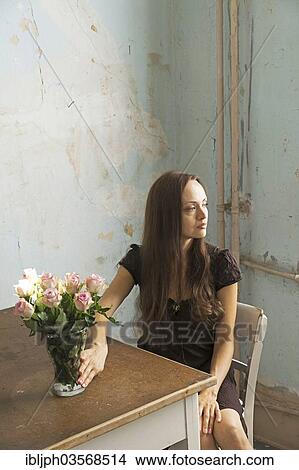 "Young woman sitting at a table with flowers in a vase, Germany, Europe" View Large Photo Image Picture - "Young woman sitting at a table with flowers in a vase, Germany, Europe". Fotosearch